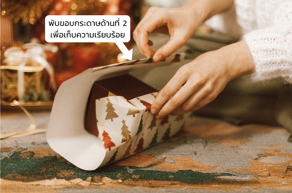 วิธีห่อของขวัญแบบง่าย ๆ : จับปลายกระดาษอีกด้านพาดบนกล่องโดยทับส่วนปลายกระดาษอันแรก